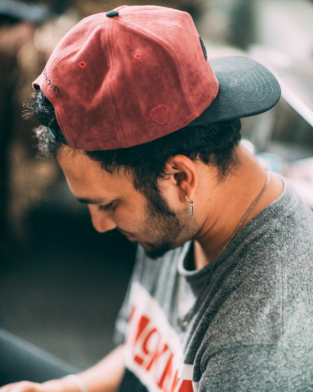 Hombre con camisa gris de cuello redondo y gorra roja