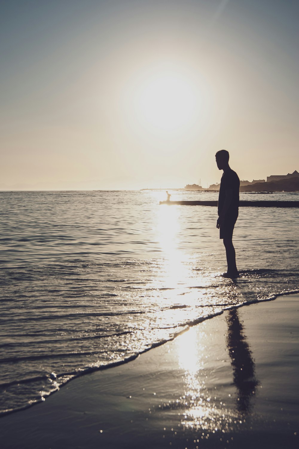 silhouette of man standing on beach during sunset