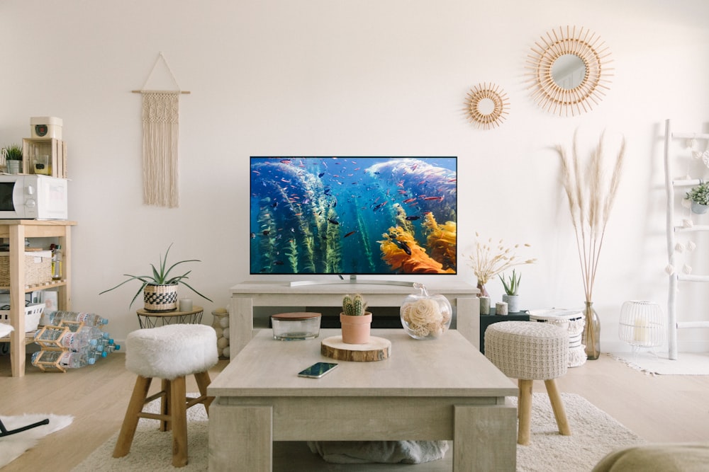 black flat screen tv turned on near white wooden table