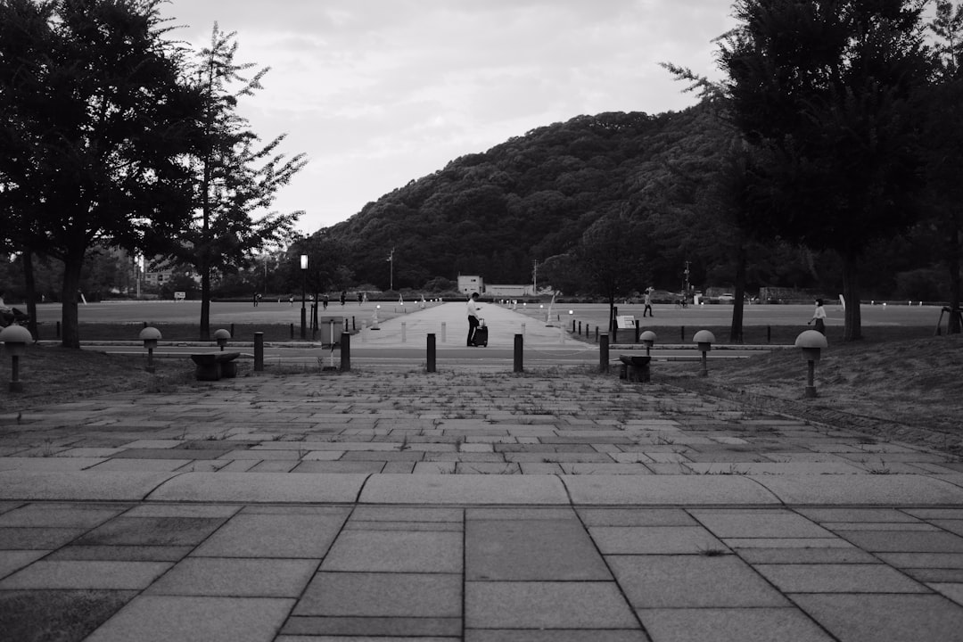 grayscale photo of people walking on sidewalk near body of water