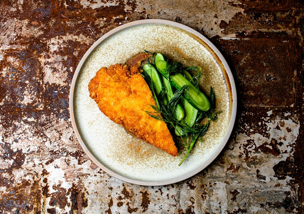 peixe frito com vegetal verde na tigela de cerâmica branca