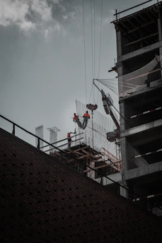 Technicians carefully installing safety nets on a tall building framework.