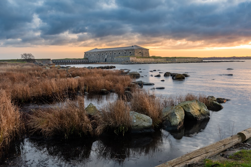 brown concrete building near body of water under cloudy sky during daytime