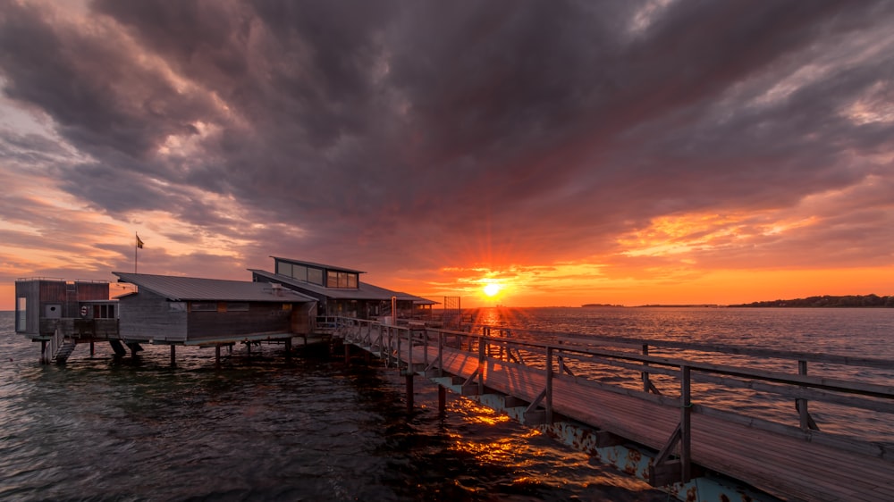 brown wooden dock on sea during sunset