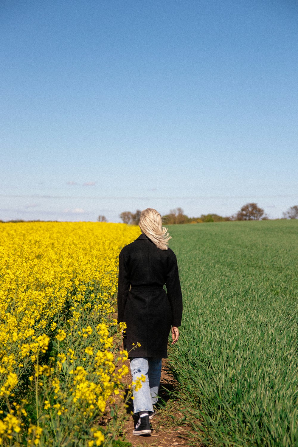 woman in black coat standing on green grass field during daytime