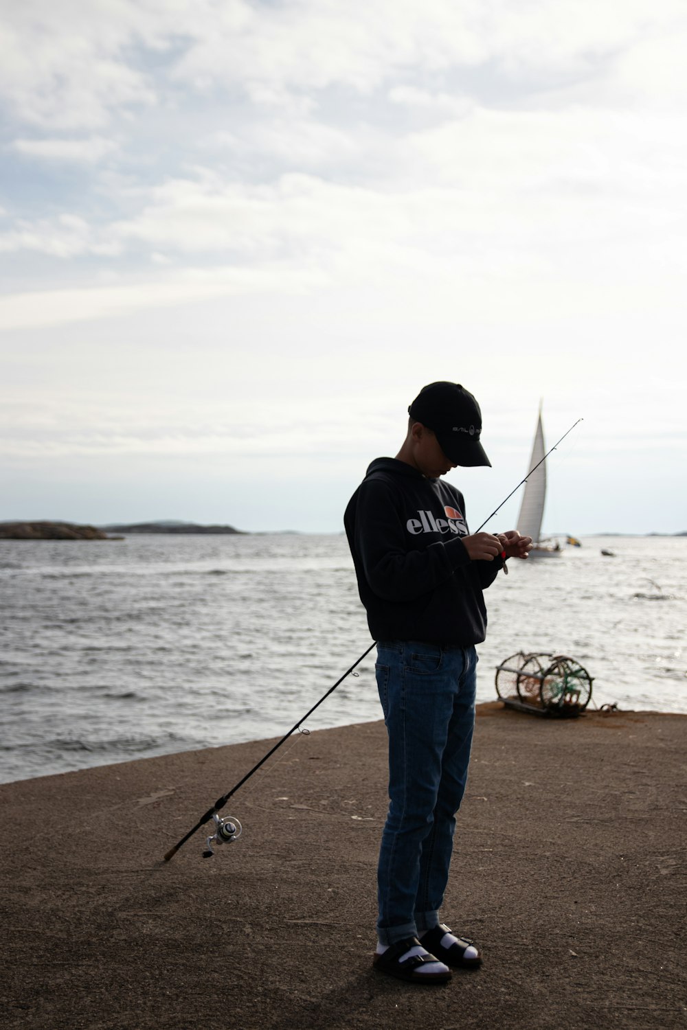 man in black t-shirt and blue denim jeans fishing on sea during daytime