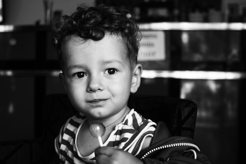 grayscale photo of boy in black and white striped shirt