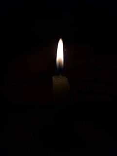 A candle being lit, with soft flames illuminating the surrounding area.