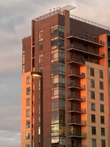 A modern multi-family residential building completed by Joma Constructions, bathed in warm sunlight.