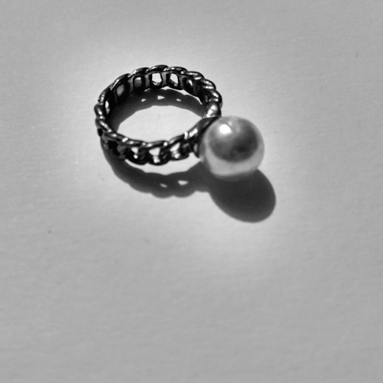 Close-up shot of a matte black band ring resting on a charcoal textured surface with soft shadows.