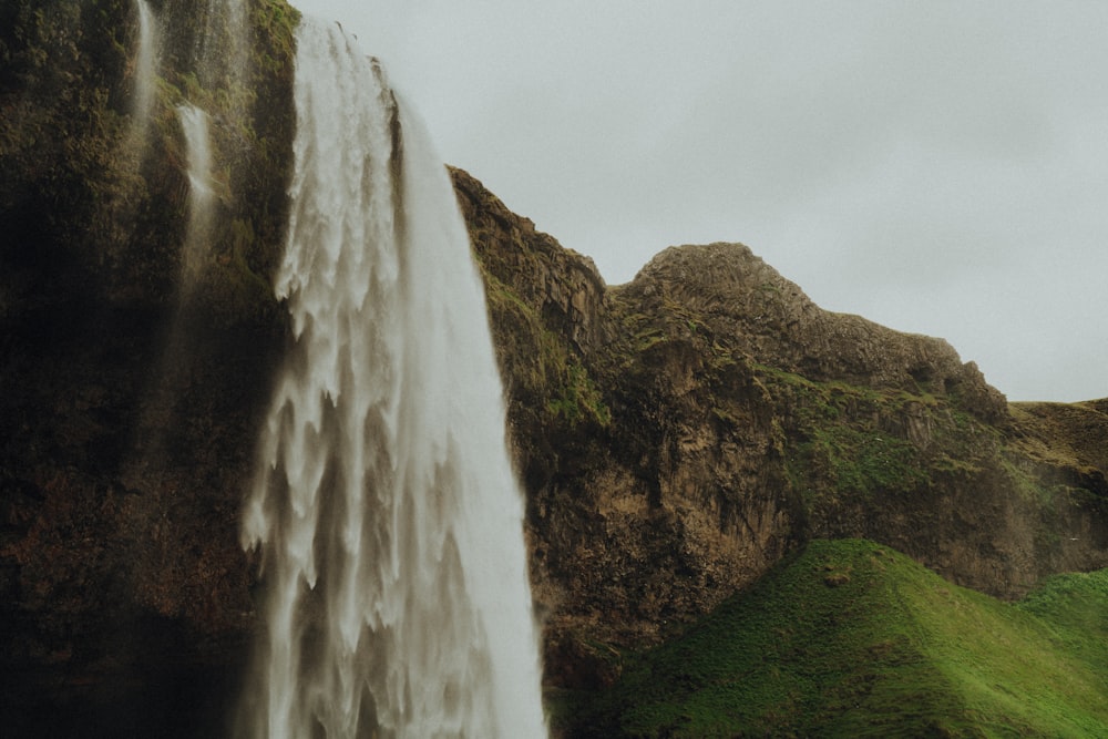 waterfalls on green grass field during daytime