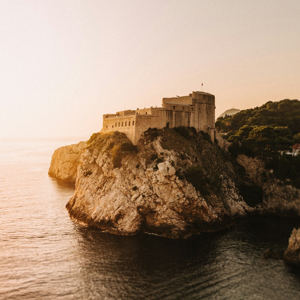 brown concrete building on cliff by the sea