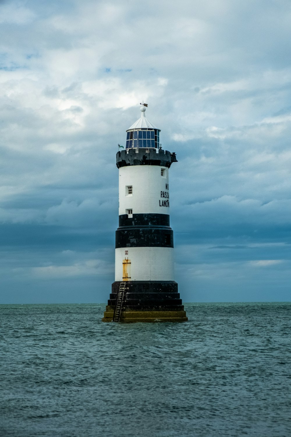 white and black lighthouse under cloudy sky during daytime