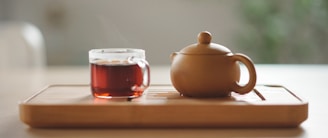 white ceramic teapot beside clear glass cup with red liquid
