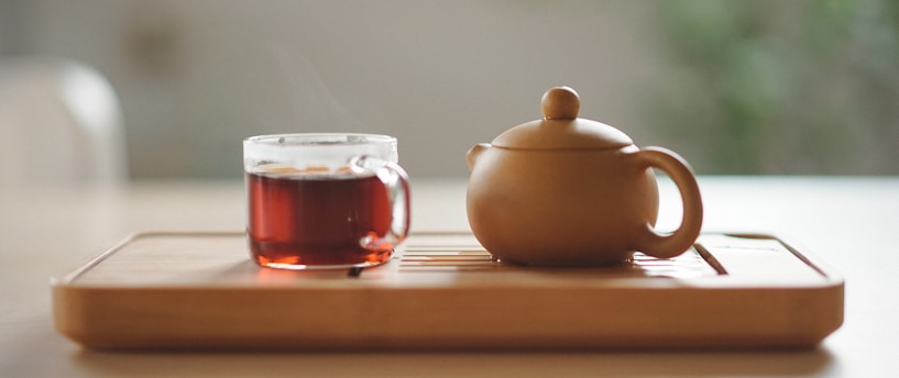 white ceramic teapot beside clear glass cup with red liquid