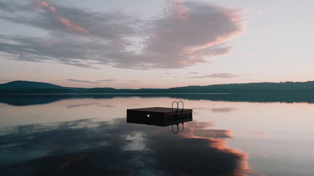 brown wooden bench on body of water under cloudy sky during daytime