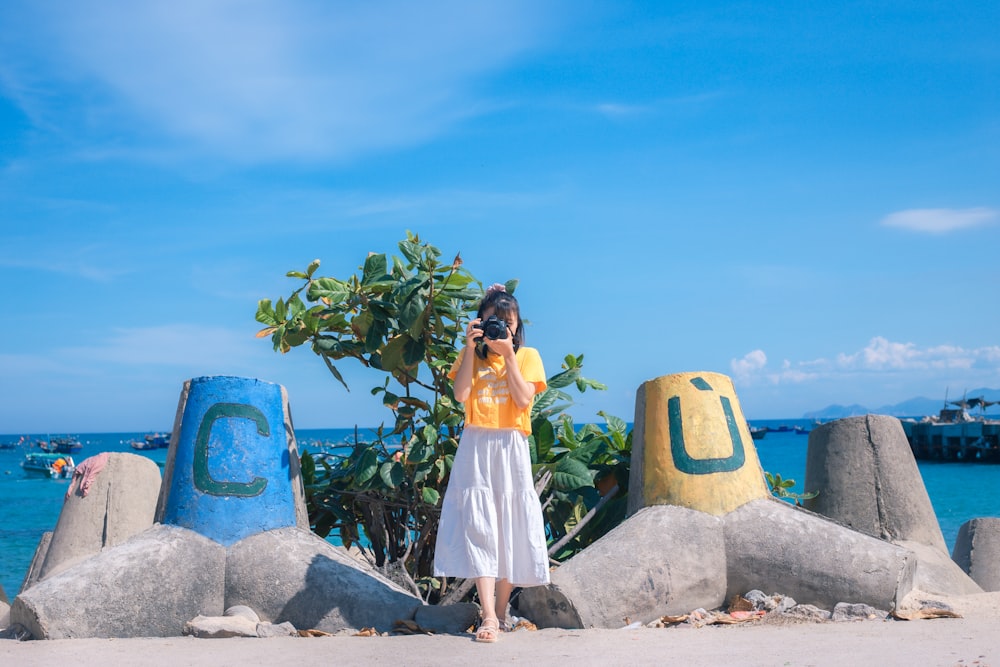 woman in white dress standing on gray rock during daytime