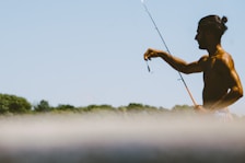 man in black tank top fishing during daytime