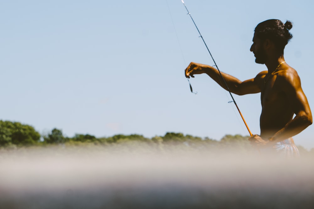 man in black tank top fishing during daytime