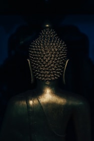 A brass sculpture catching the light, showcasing intricate detailing against a charcoal backdrop.