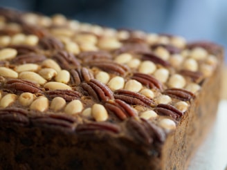 A close-up view of a richly textured loaf, adorned with a surface pattern of whole pecans and other nuts embedded into the surface.