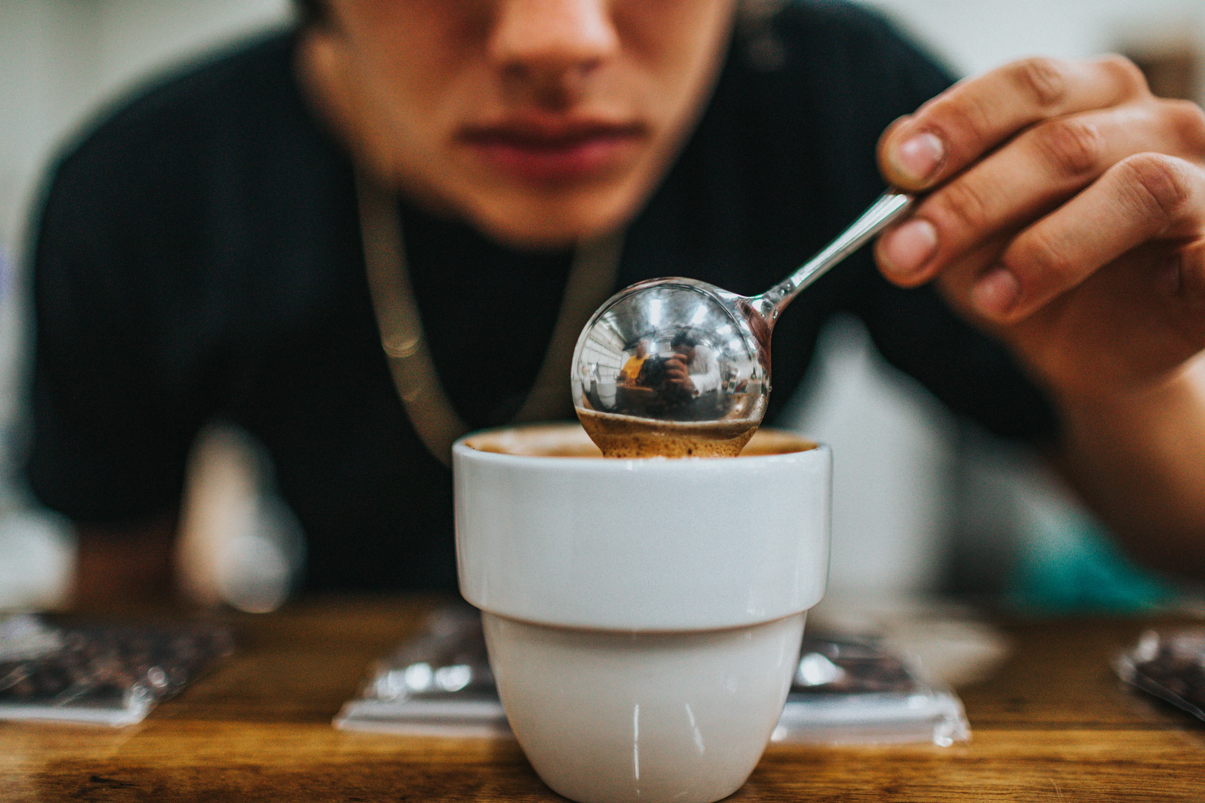 Guest tasting coffee with a cupping spoon
