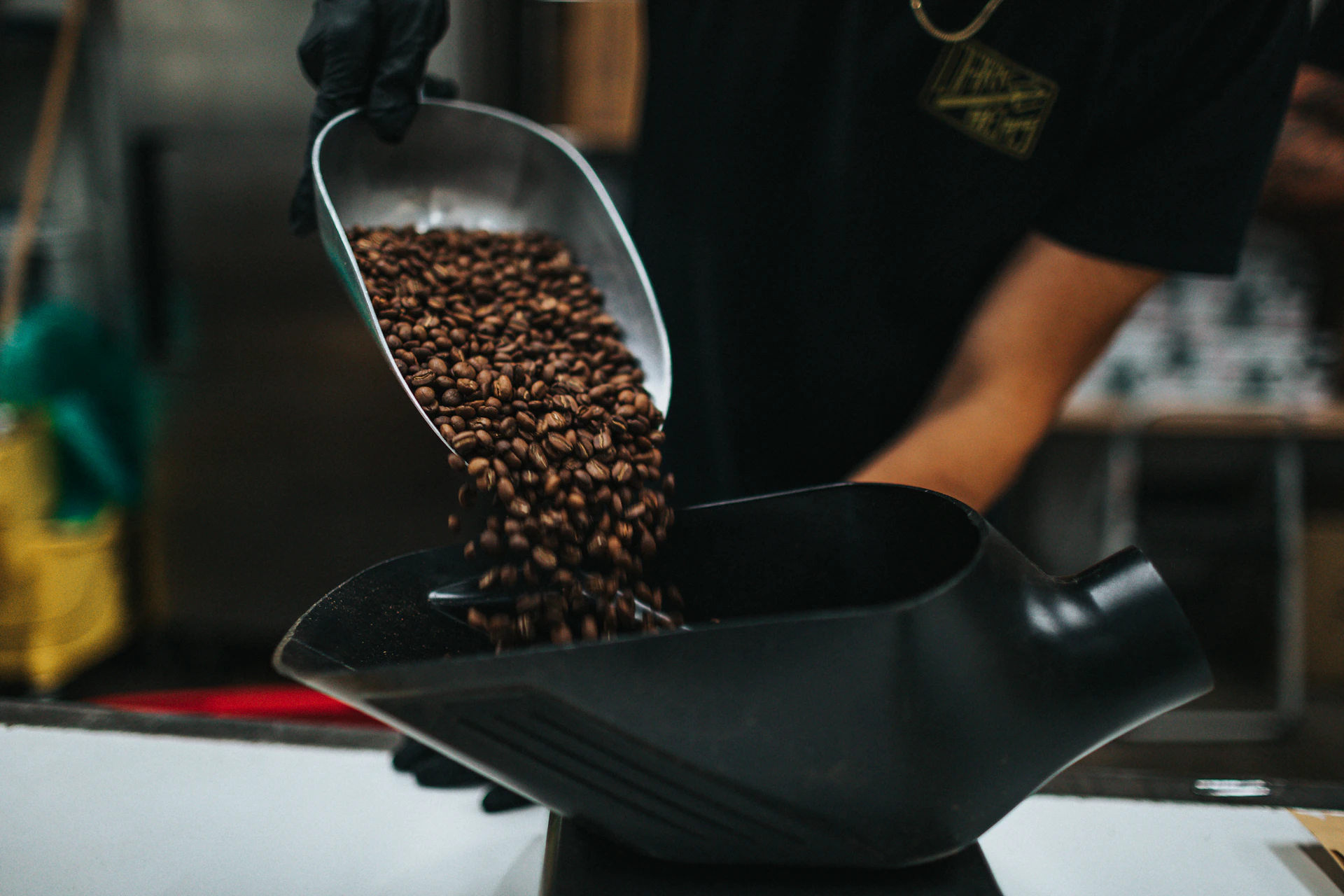 Artisan carefully pouring freshly roasted coffee beans into a traditional grinder, surrounded by vibrant Mexican textiles.