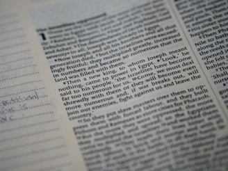 A close-up of a printed page from a book with text in columns. The text includes a header with a number and a small portion of handwritten notes is visible on a lined section on the left side.