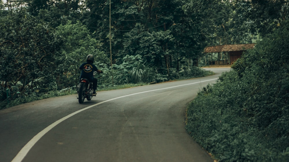 uomo in giacca nera che guida la moto sulla strada durante il giorno