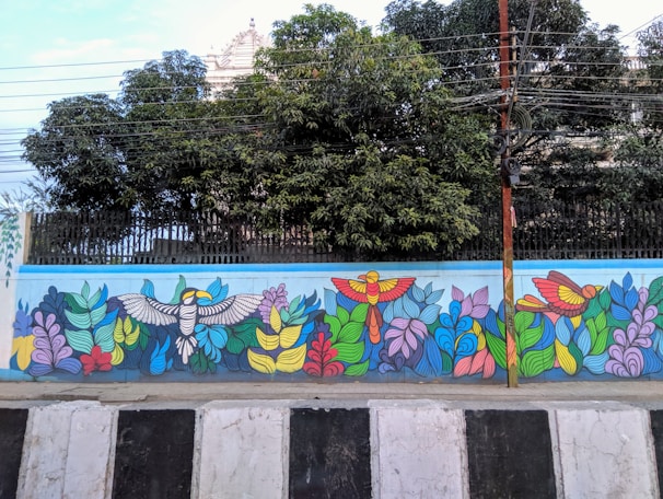 Vibrant mural detail showing colorful tropical birds intertwined with graffiti-style lettering.