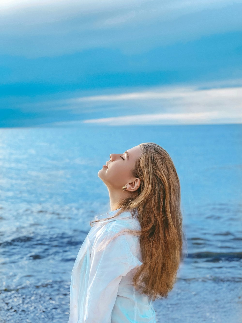 femme en chemise blanche debout près de la mer pendant la journée