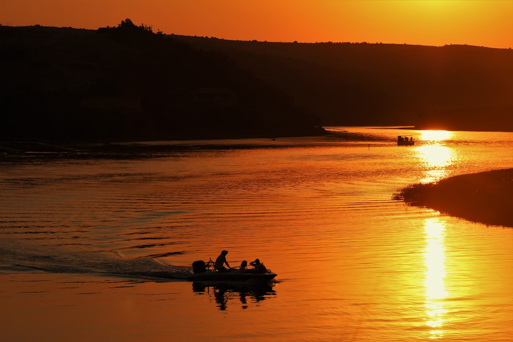 silhouette of people riding boat on sea during sunset