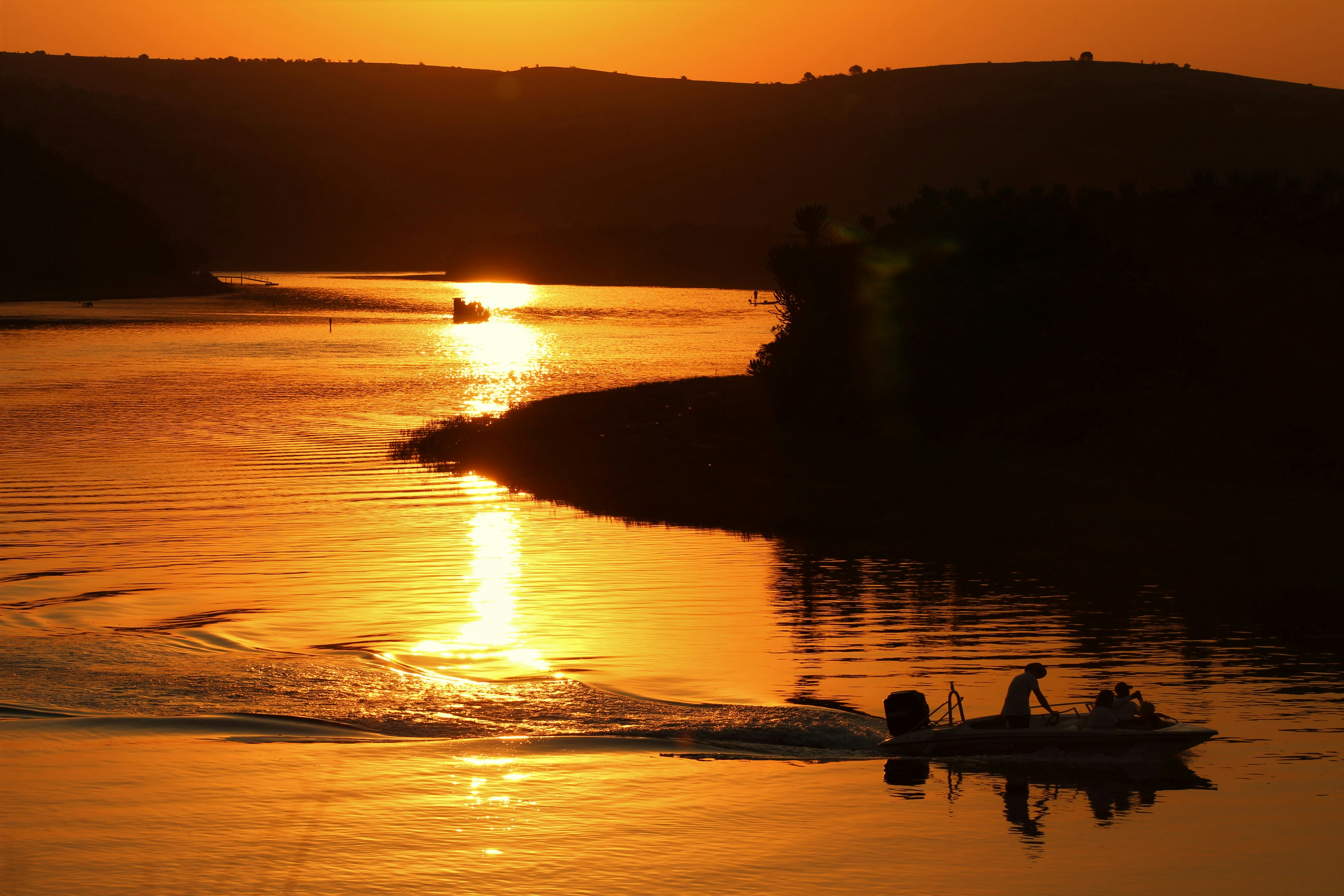 silhouette of 2 people riding on boat on sea during sunset