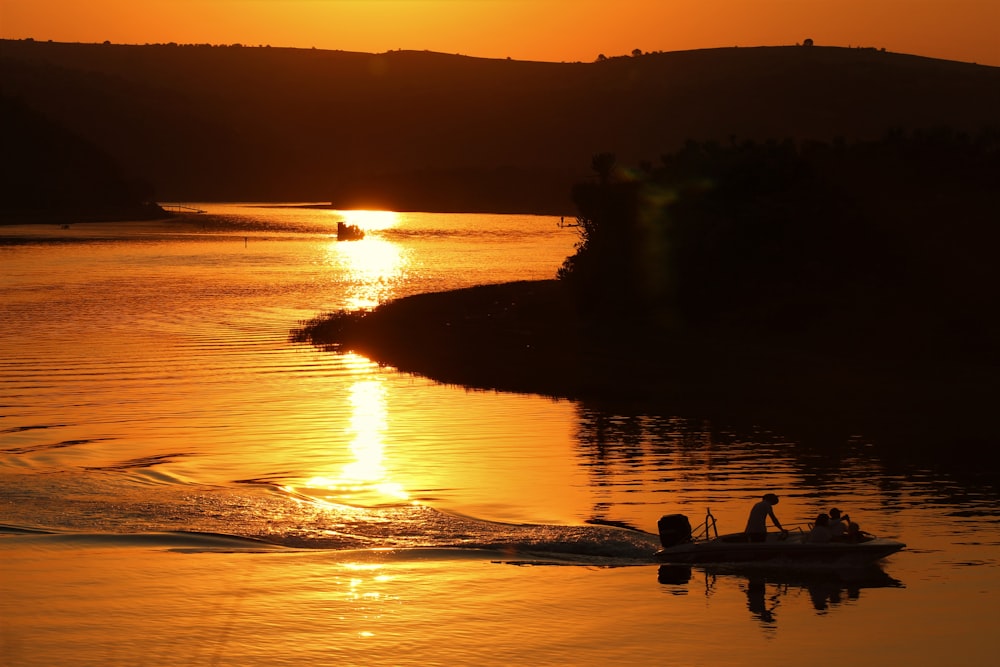 silhouette of 2 people riding on boat on sea during sunset