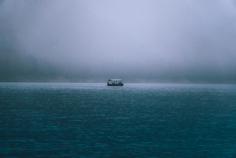 black boat on sea during foggy weather