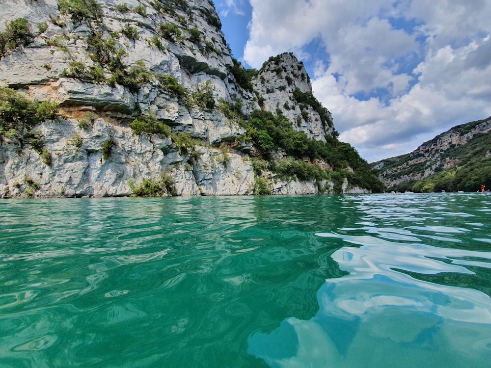 gray rocky mountain beside body of water during daytime