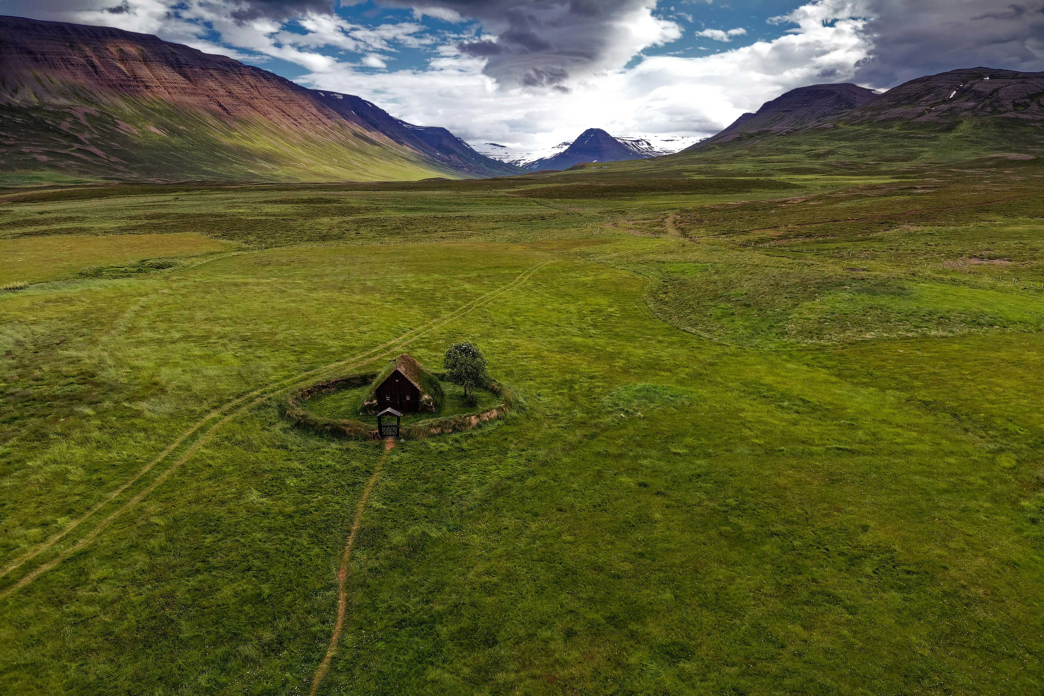green grass field near mountain under blue sky during daytime