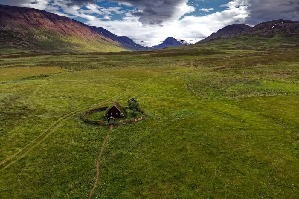 green grass field near mountain under blue sky during daytime