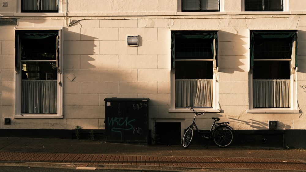 black bicycle parked beside white wall