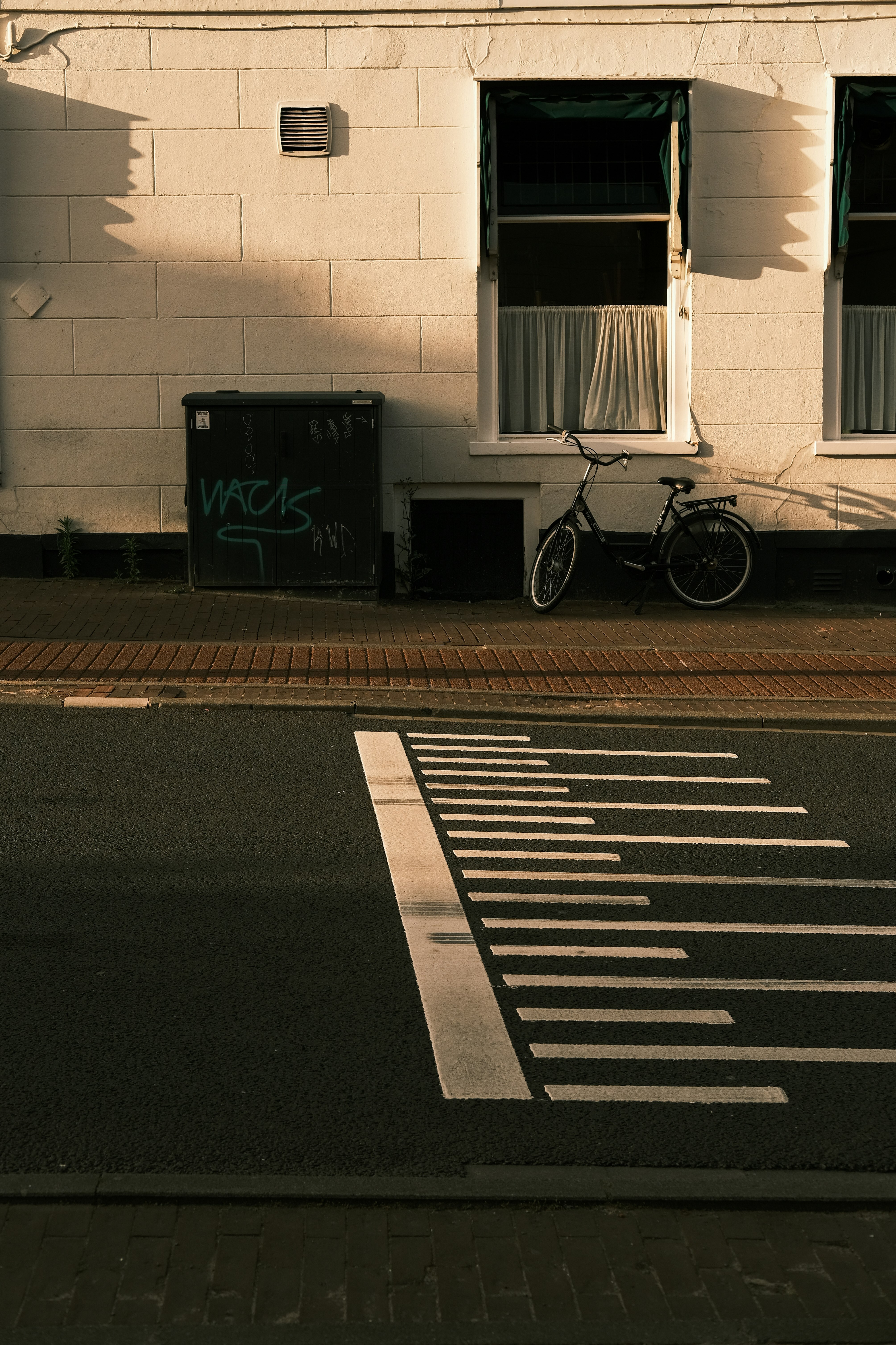 black bicycle parked beside white wall