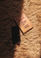 A cozy Arabic reading nook with headphones and a glowing lamp illuminating a stack of audio books.