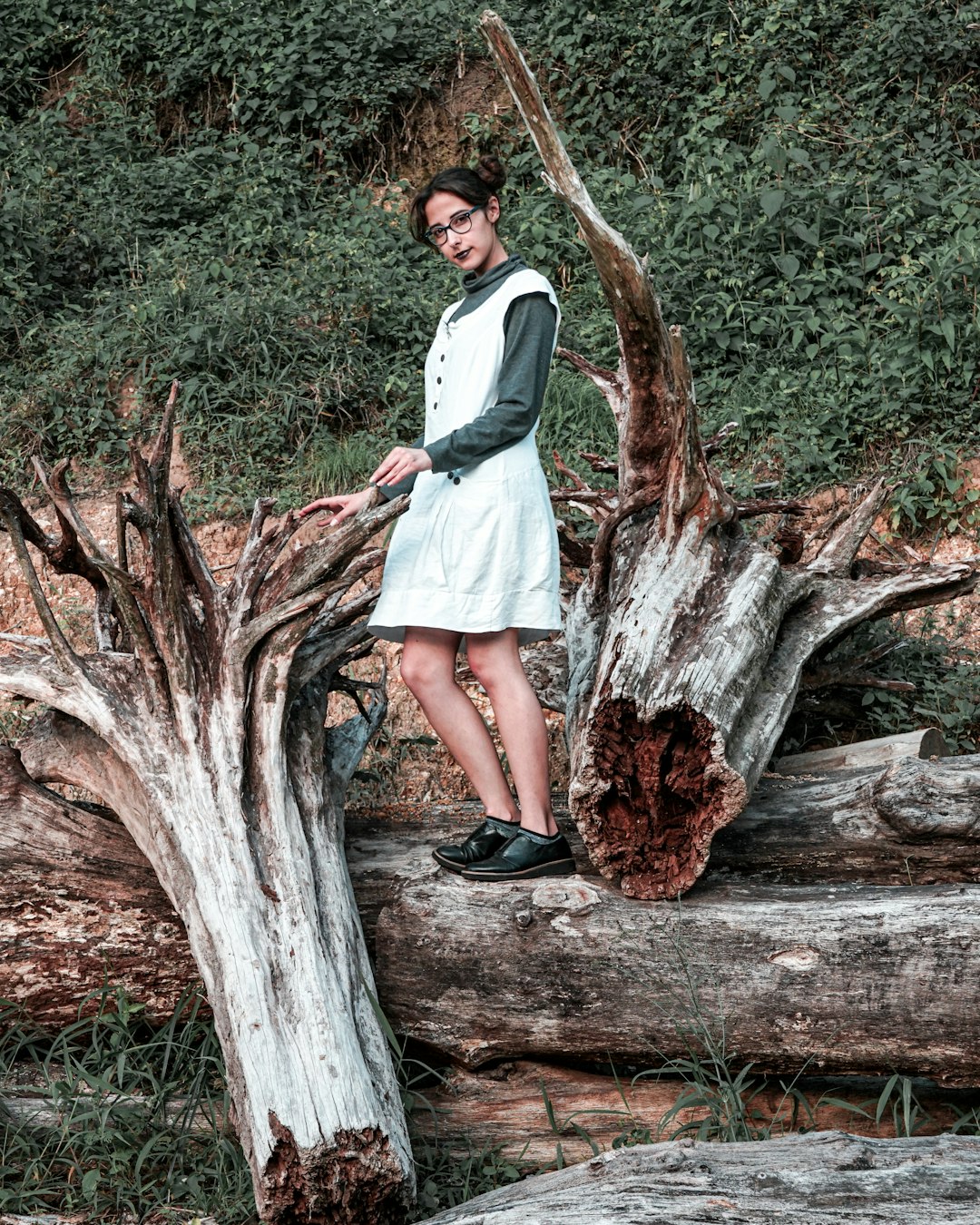 woman in white long sleeve dress standing on brown tree trunk