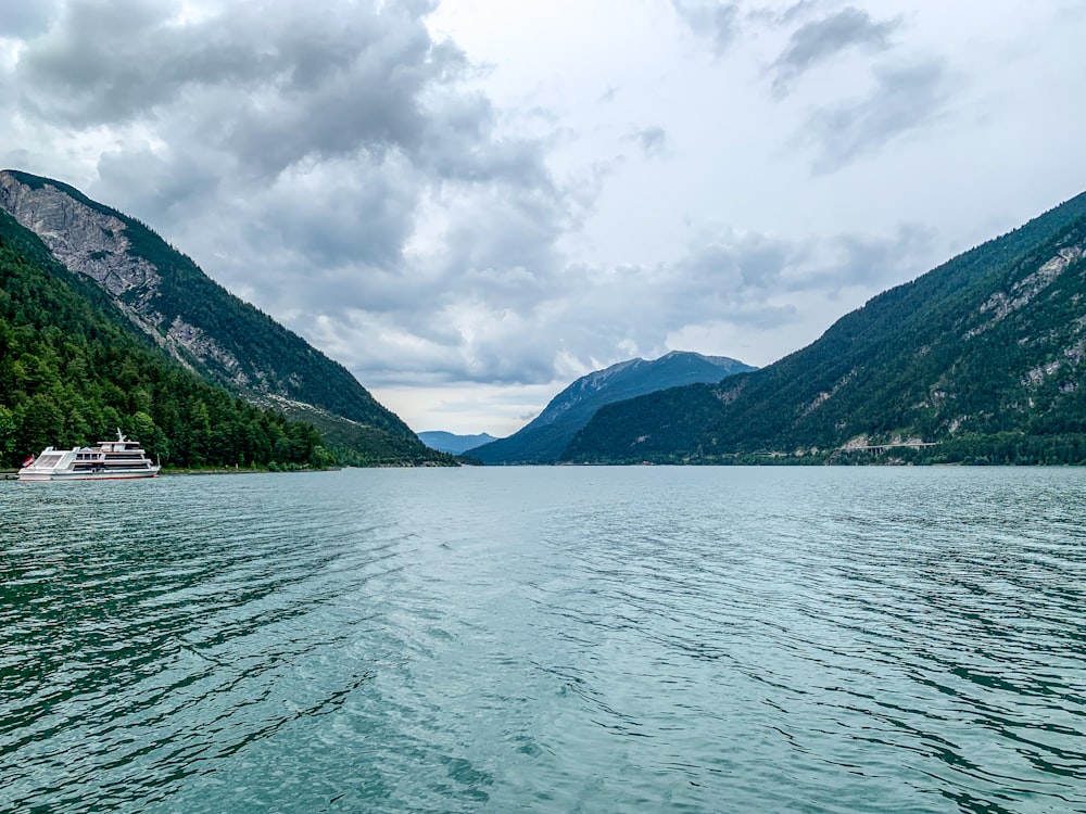 body of water near mountain under cloudy sky during daytime
