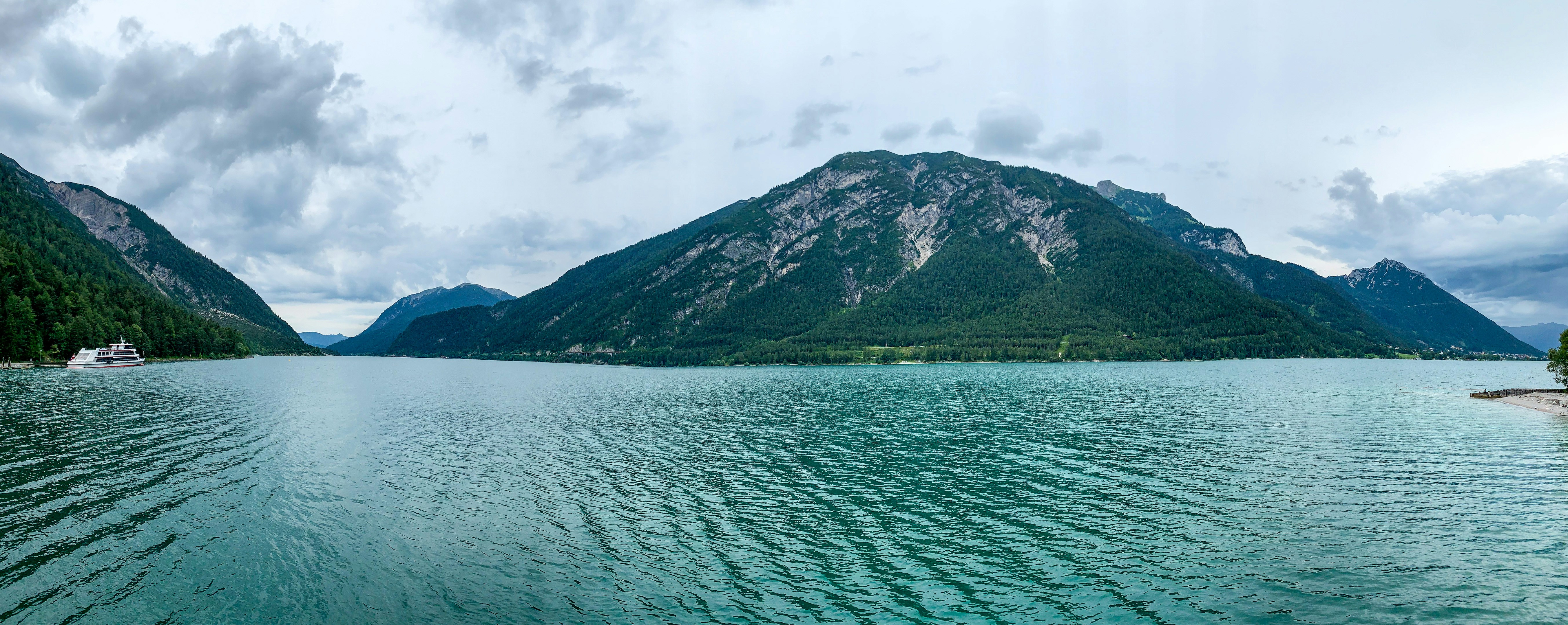 green mountain beside body of water during daytime