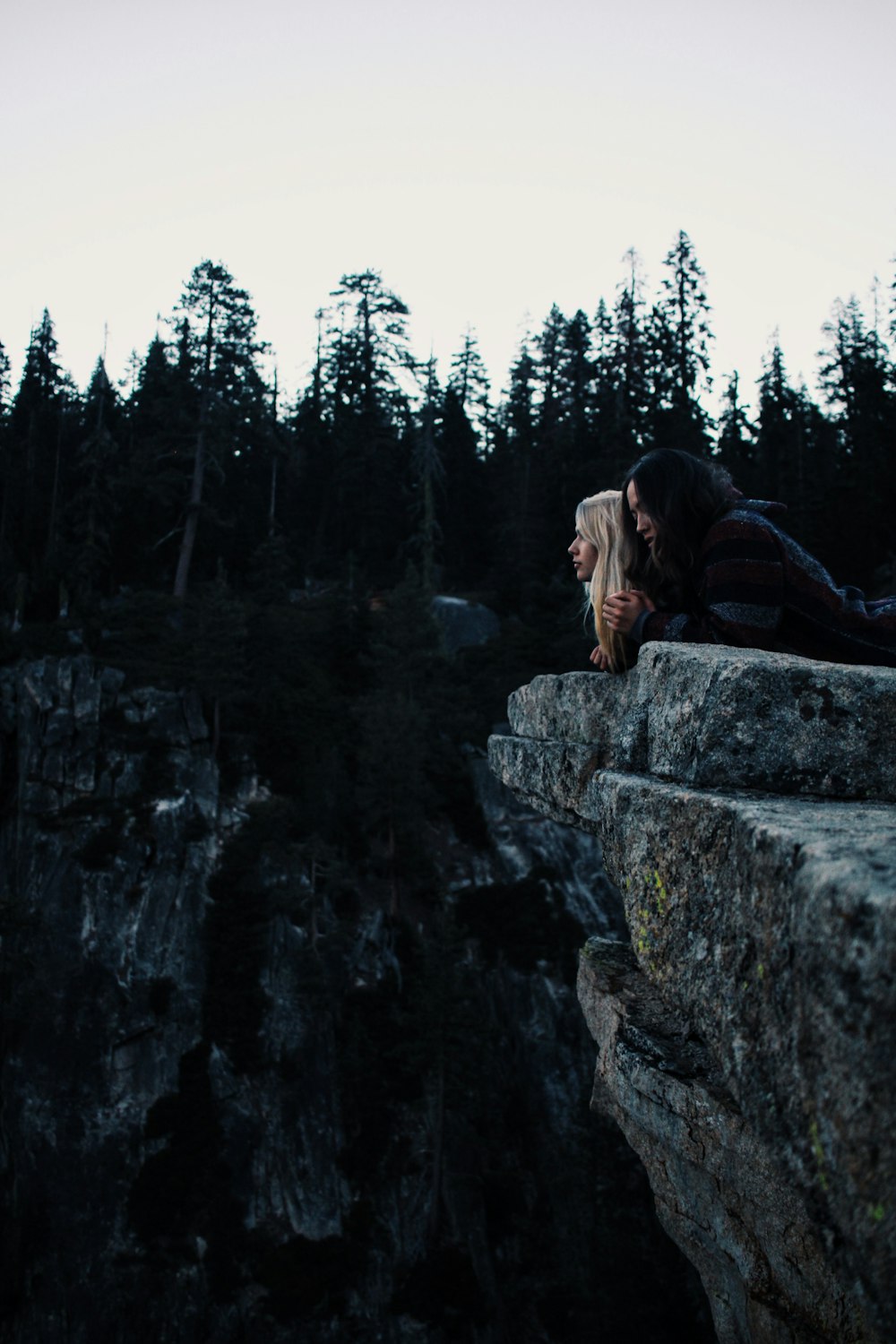 Femme en veste noire assise sur le rocher