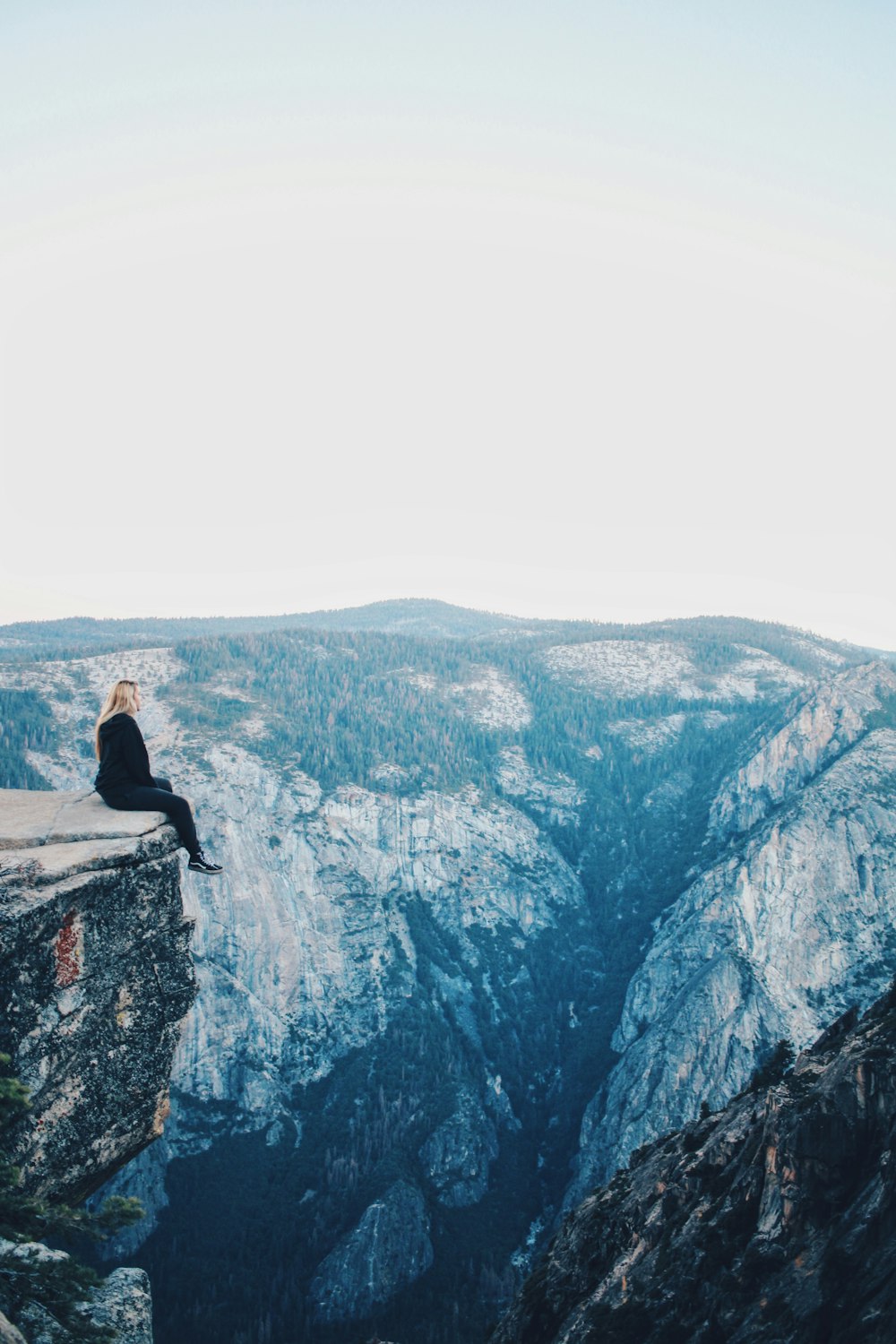 man in black jacket sitting on rock mountain during daytime