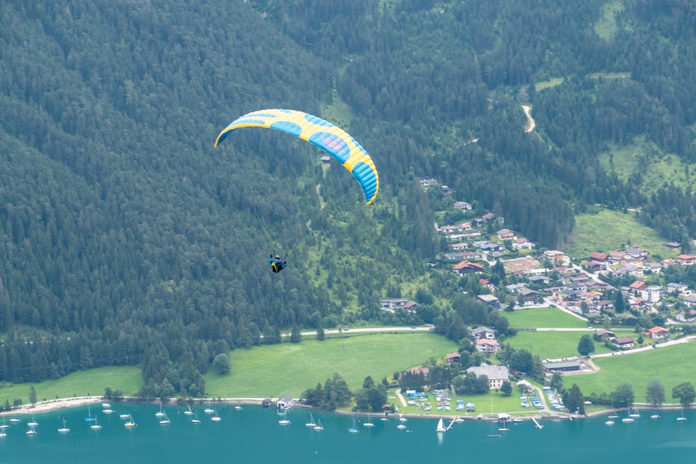 people riding parachute over green mountains during daytime