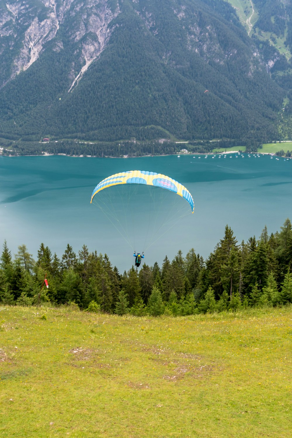 person riding parachute over green trees and mountain during daytime