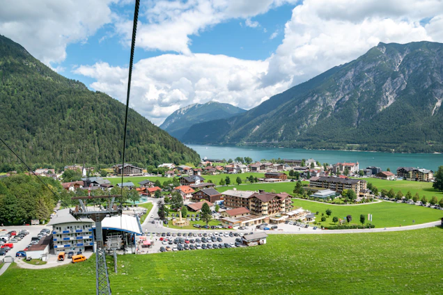 A professional taxi driver assisting a passenger with luggage in a scenic alpine village.