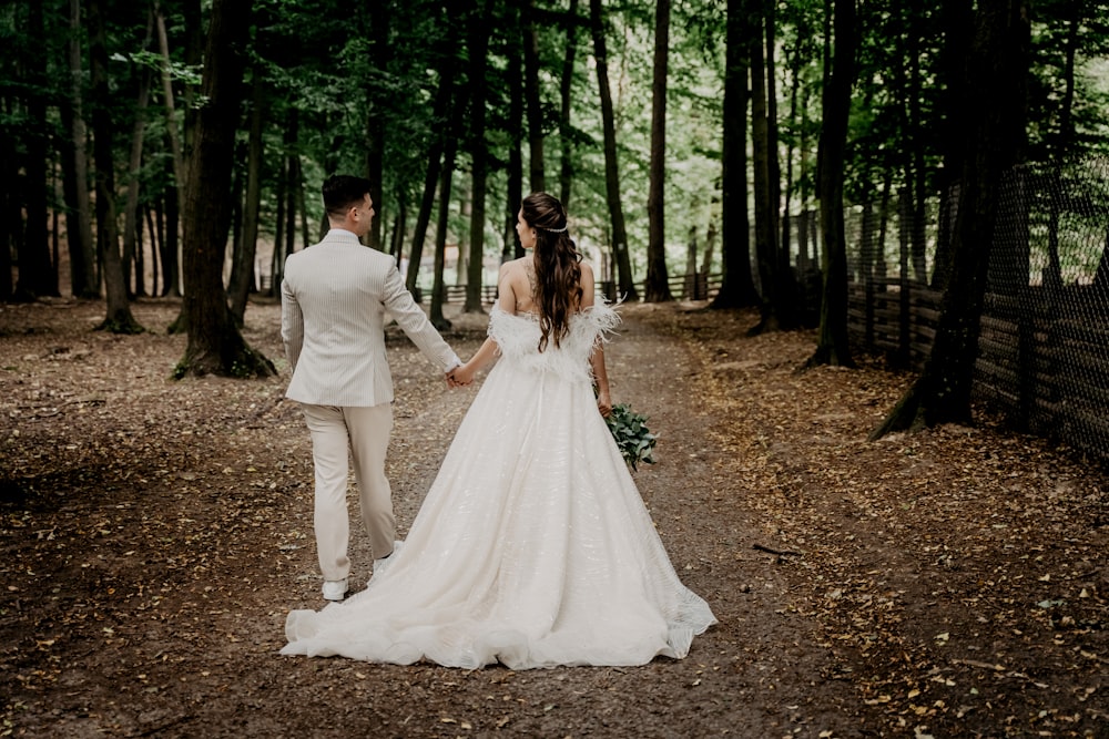 man and woman in white wedding dress walking on forest during daytime